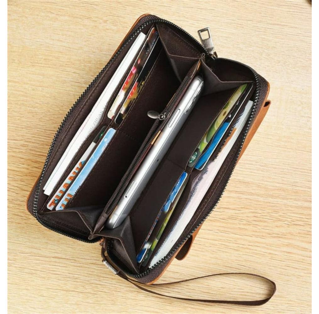 Open brown leather wallet with items on a wooden surface