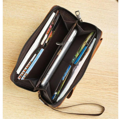 Open brown leather wallet with items on a wooden surface